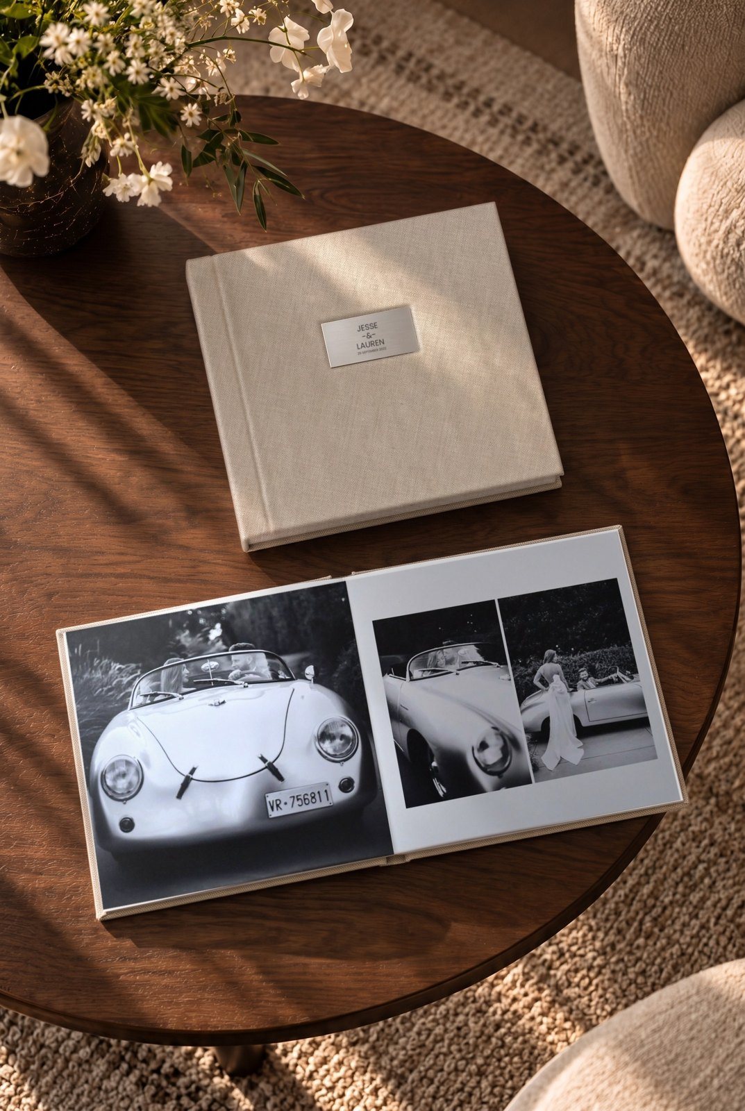 A natural linen album open on a walnut table, a black and white wedding spread lying flat